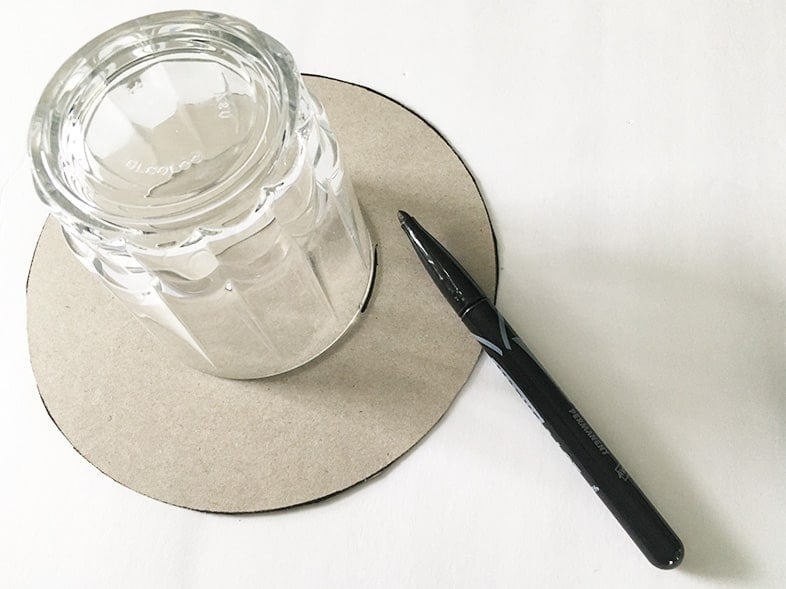 Photo of a black marker, glass and cardboard from a cereal box used as a base for a hairpin mirror diy.