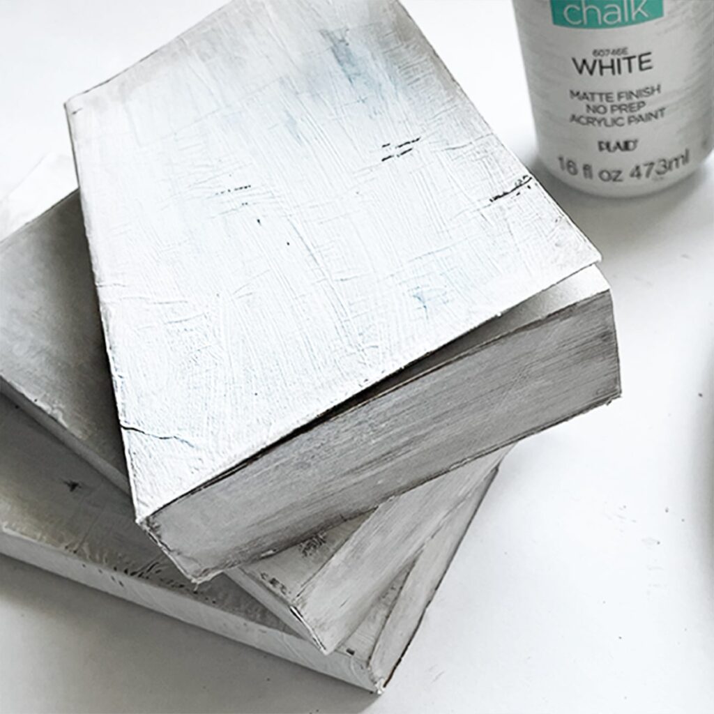 Square photo of finished distressed books painted white with chalk paint.