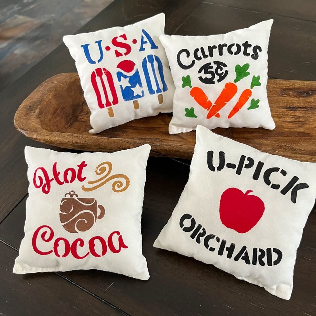 Square feature image of four finished mini pillows - USA popsicles, 5-cent carrots, Hot Cocoa and U-Pick Orchard.