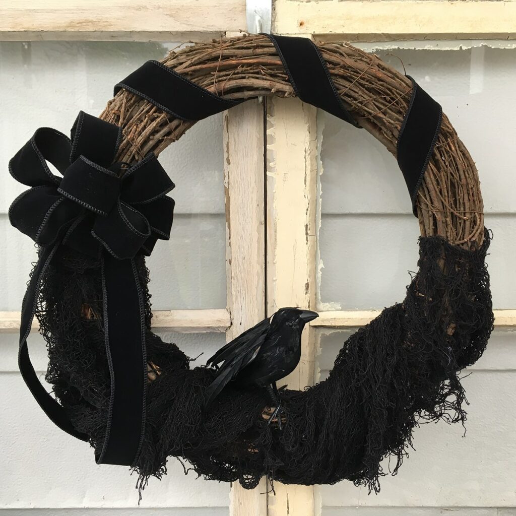 Square feature photo of a finished Black Crow Wreath placed on an old window.