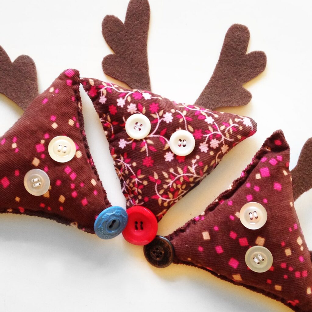Square photo of three finished reindeer beanbags with different button noses made of pink and brown corduroy fabric.