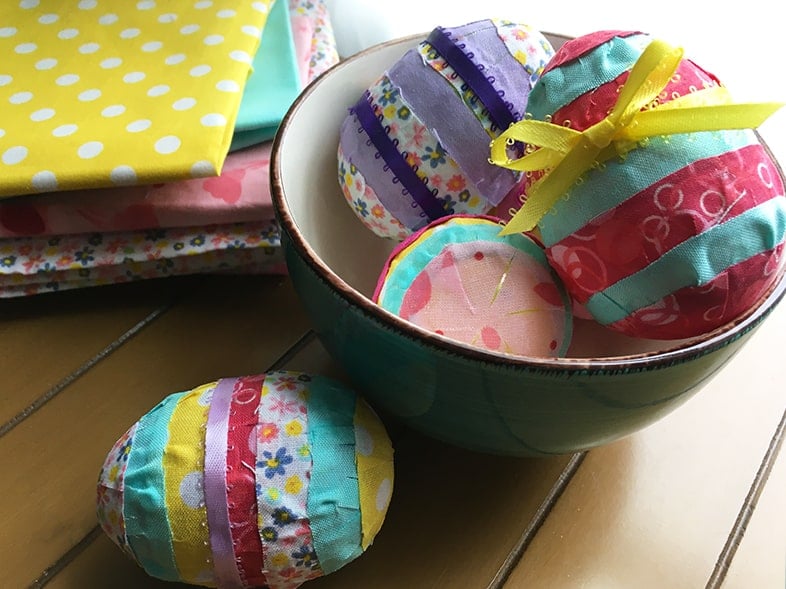 Horizontal photo of a finished bowl of scrap fabric eggs on a table.