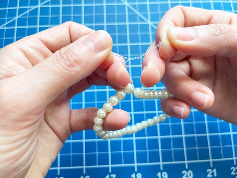 Photo of an overhand knot being made to finish a stretch bracelet for a vintage brooch pin bracelet.