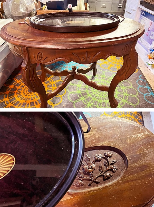 Before photo of a thrift brown oval table picked up at the thrift store. It has ornate curved legs with floral and leaf carvings. The top center is an deep carved out oval with a flower pattern. There is a side view of the brown stained table and below that is a top down view of the worn table top. This table needed TLC as there were missing carved areas to fill and scratches to the original stained finish.