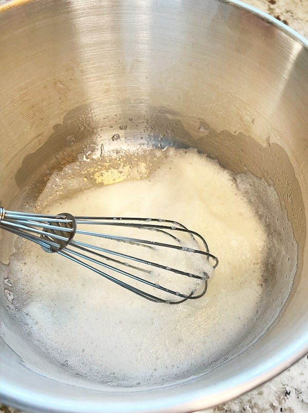 Process and closeup photo of egg white that have been whipped with a whisk until light and fluffy with peaks forming. This is the first step in making the coconut filling for making a delicious filling for a coconut-filled chocolate Bundt cake.