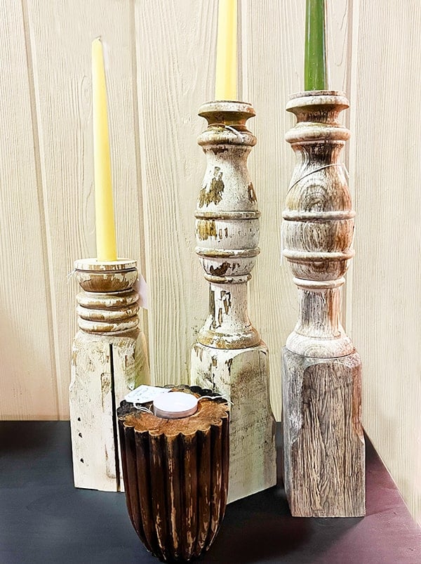 Shown are three chippy white taper candle holders made from bed posts. In the front is a dark wood carved with vertical post top turned upside down to make a tealight holder.