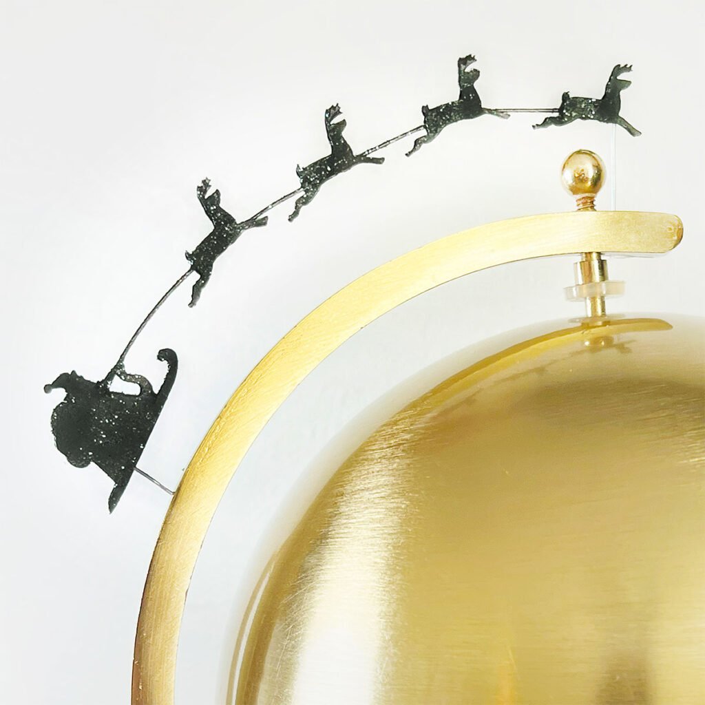 Closeup of a black silhouette of Santa's Sleigh and Reindeer added to an old brass bankers globe.