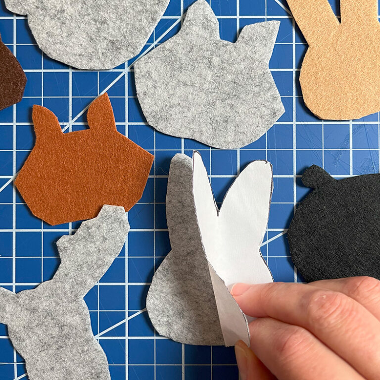 Removing the paper backing from felt pattern pieces after cutting all of them out.