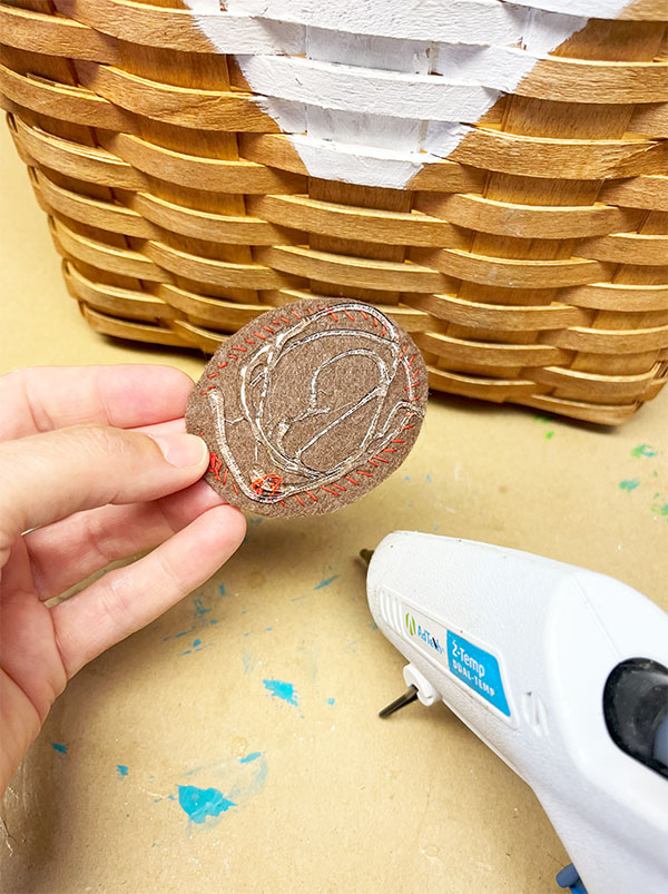 Using hot glue to glue the felt nose to an upcycle reindeer basket.