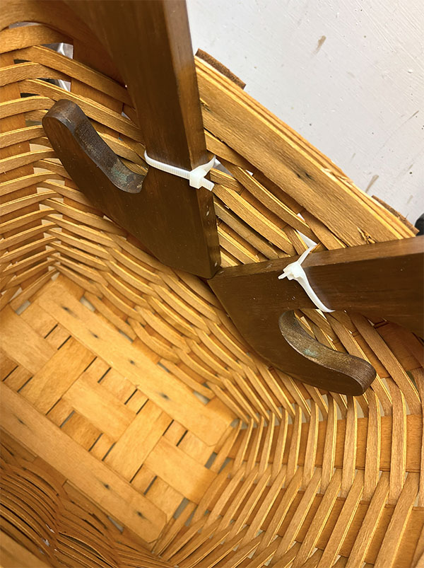 Closeup photo showing how the wood antlers were attached to the inside of a wicker basket with zip ties to upcycle the basket into a reindeer basket for the holidays.