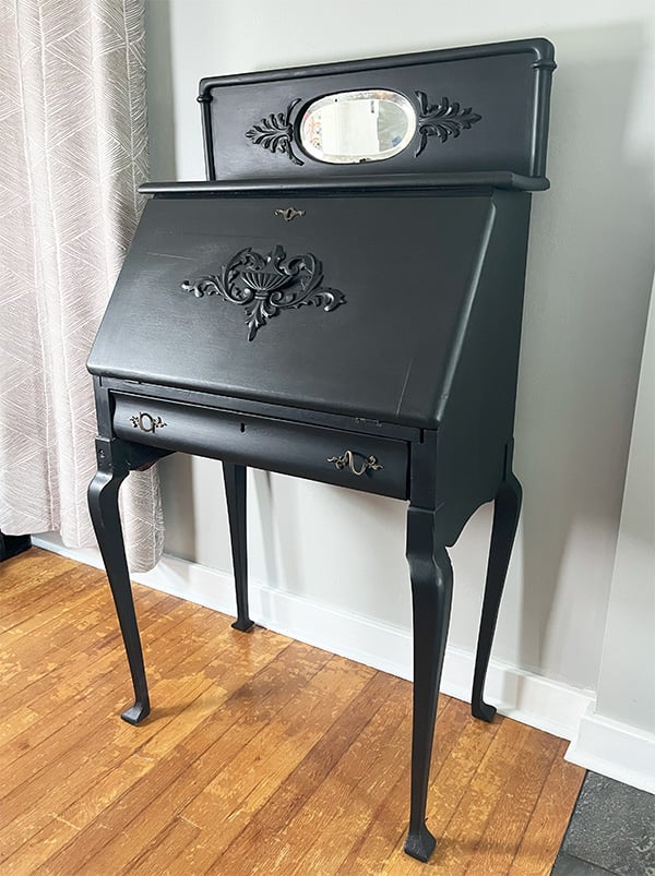 Refurbished desk from 1923. This desk on tall legs has the original oval mirror at the top and decorative trim pieces. Show here with a new coat of flat mineral paint in caviar. The drawer and fold out desk top also have the original hardware and wood decorations.