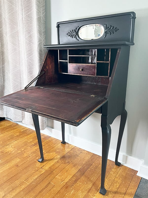 1923 refurbished desk from 1923. This desk on tall legs has the original oval mirror at the top and decorative trim pieces. Show here, the inside was left the original mahogany with aged patina as a nod to the vintage piece it is. The outside got a new coat of flat mineral paint in caviar.