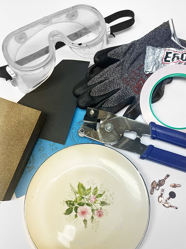 Photo of supplies including safety glasses, gloves, E6000, tile snips (optional), foil tape, a plate, jewelry bails and sand paper.
