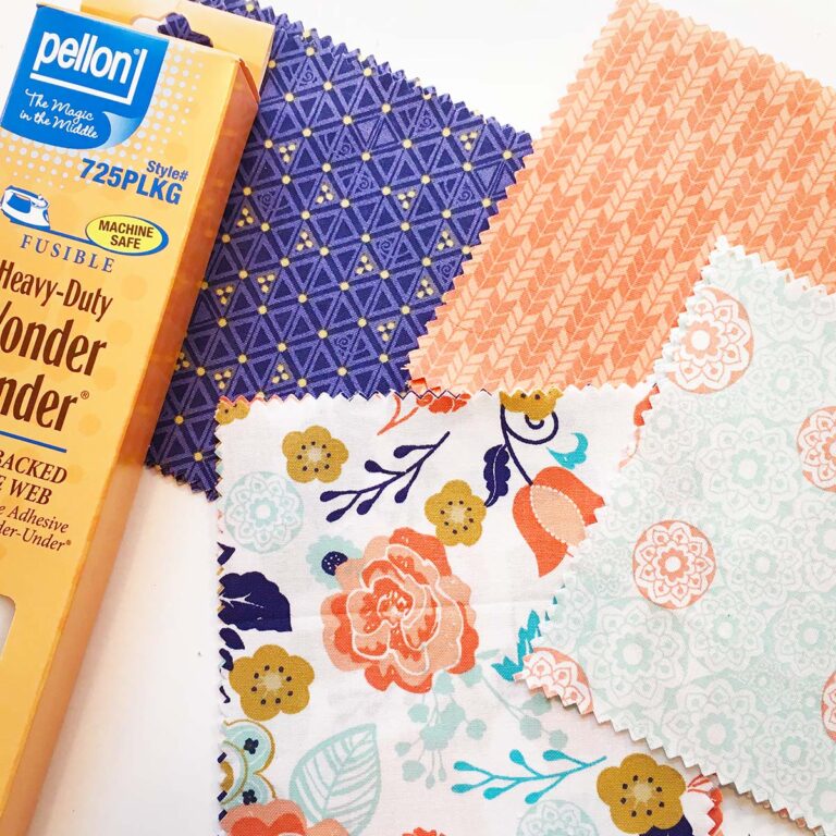 Closeup of colorful swatches used in peach pattern, blue pattern and florals with a package of Pellon Wonder Under fusible web to the left.
