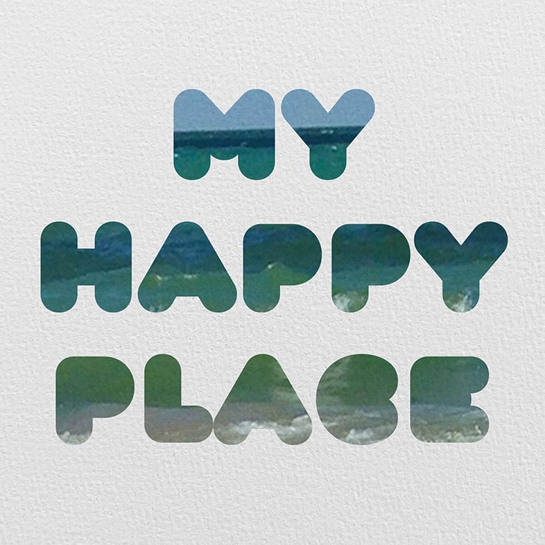Shown is a feature photo for a post offering 18 free beach prints. These are all photographed and designed by me. Some have text over the photos, some are just beautiful tropical beach and lake shots. A nice mix of colors, scenes and typography art. Each has it's own story and this feature is of rounded bubble type that says 'MY HAPPY PLACE' with a picture of the beach sand stretching out from green to dark blue water then light blue sky inset into the type. The photo type is on a white textured water color paper.