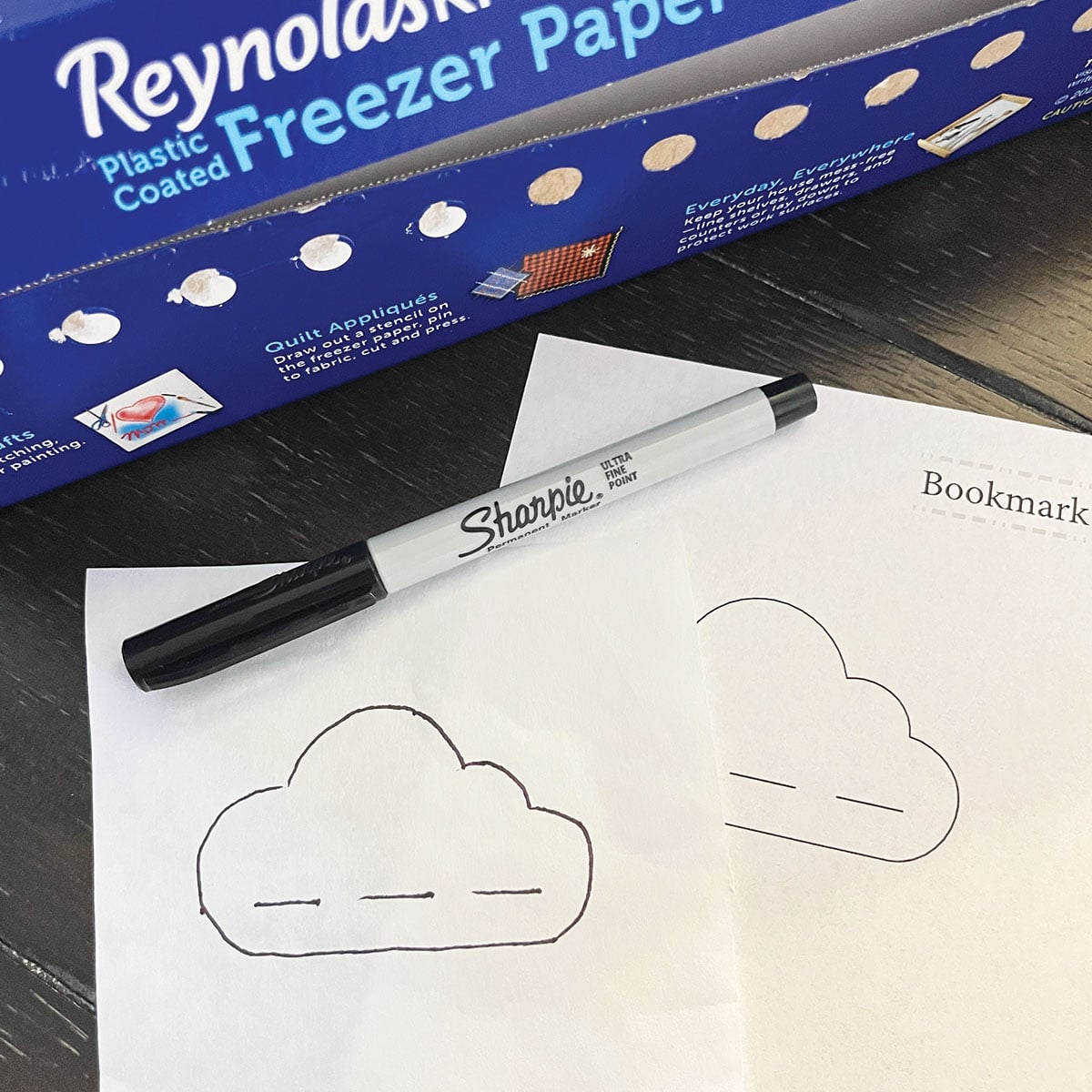 Tracing the cloud pattern shape onto a square of freezer paper.