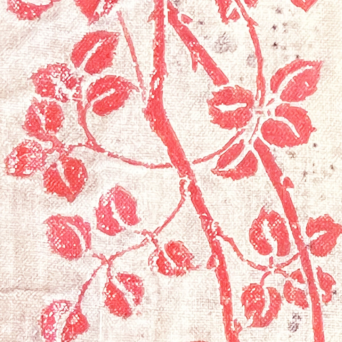 Closeup of floral pattern with leaves and vines in a sunsoaked pink hue from an old book cover.