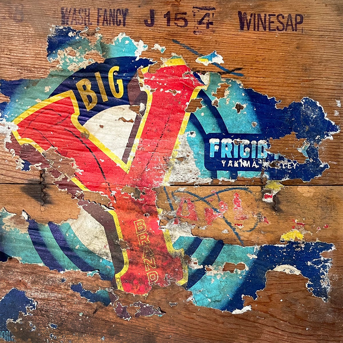 Worn label on the side of an old vintage wood crate. It is a paper label that says Big Y Wash Fancy Winesap. An old graphic from an apple crate in chippy red, yellow and blue. Summer color inspiration.