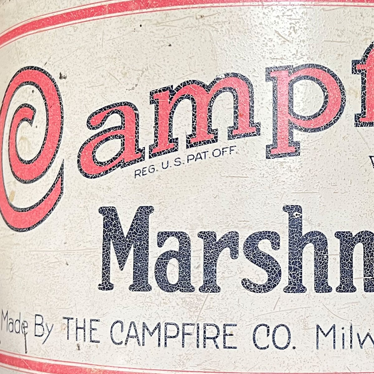 Partial photo of a campfire marshmallow tin- just one corner showing the wear and faded paint.