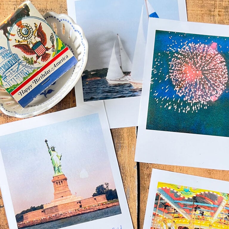Square feature and flatlay of vintage polaroid shots of firewords, sailboats, the statue of Liberty take in 1984 from the harbor. Top left is a small white dish with a vintage matchbook with an American Eagle and the white house with Happy Birthday America type at the bottom.