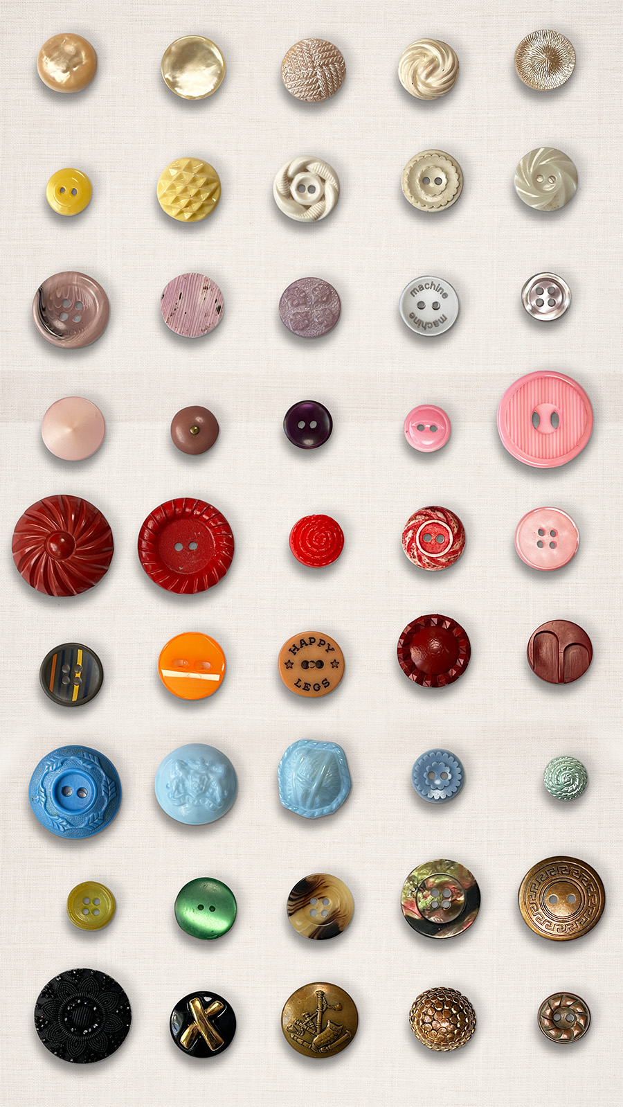 Vertical flatlay grid of 54 vintage buttons five rows and nine columns. The colors go from pearl, butter yellow, light purple, pinks, reads, orange, blue, green, tortoise shell, black and last brass. Each has a unique shape some shank buttons and some with two or four holes.