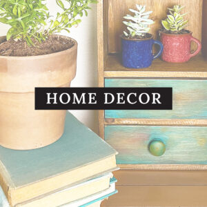 Square image button for Mobile under the Crafts menu Home Decor crafts and DIYs. Shown is an upcycled wall pocket with two torquoise painted draws, a stack of vintage books with a terracotta pot of greenery.
