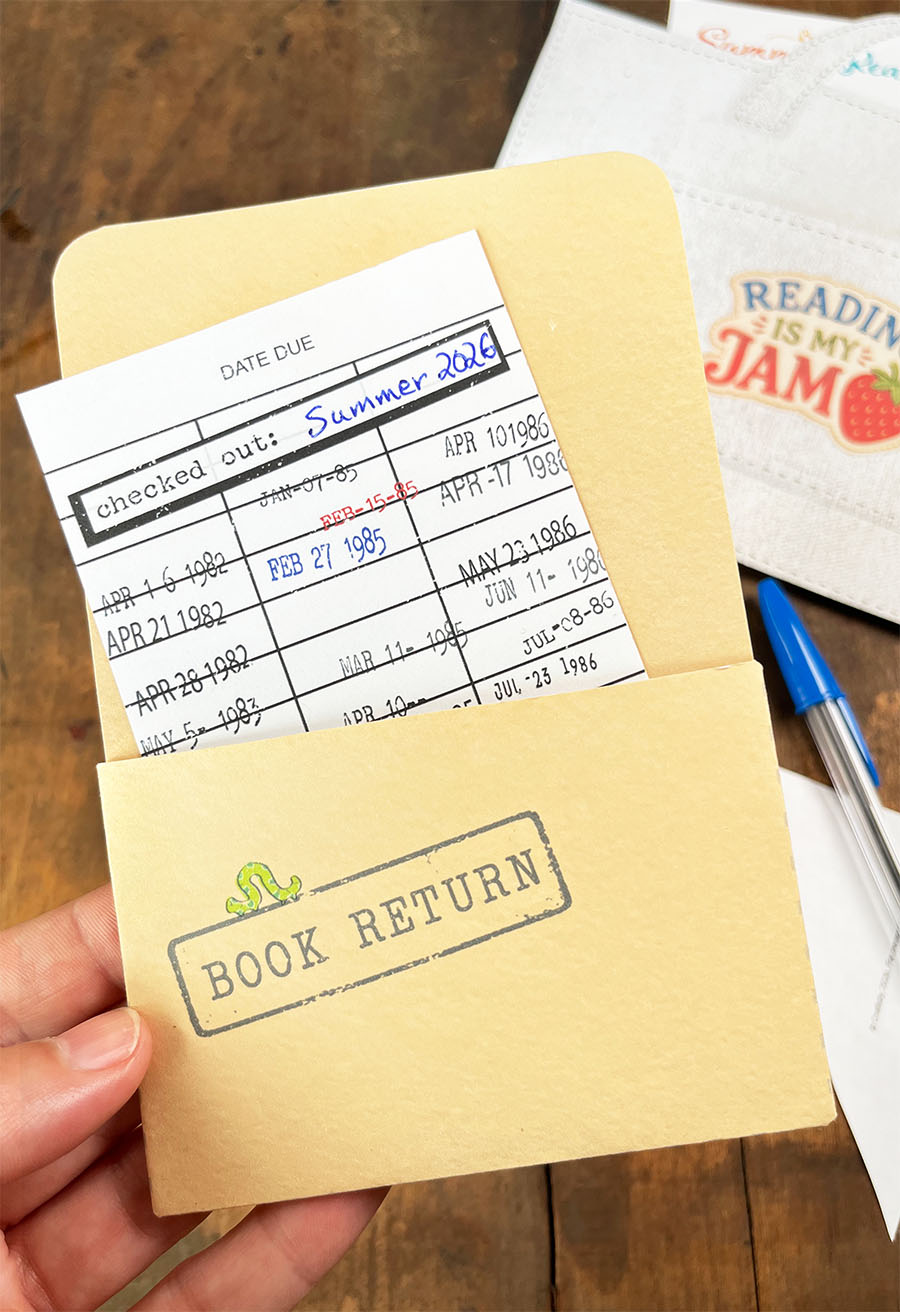A vintage library stamped due-date slip and manilla pocket with the words 'book return' stamped on the front of the pocket with an inch worm on top of the stamp. This is a free printable to cut and assemble and the fifth and final installment for The Paper Snail Club - Summer 2026 where we are filling a printable reading tote with ephemera, a custom book mark, a bookshelf coloring page, reading list, note cards and other bookish printables.