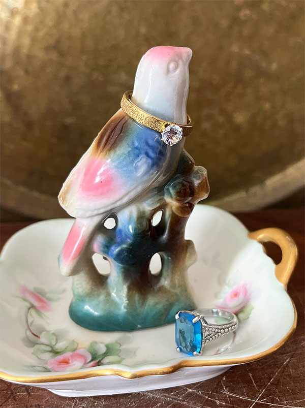 Vintage bird figurine attached to a butter pat dish to create a DIY ring holder with two rings.