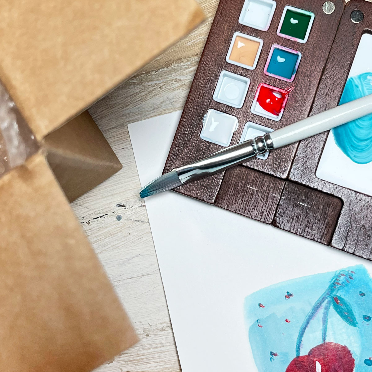 A few familiar tools, an open shipping box, and a page of paint experiments. The objects change over time, but the impulse to create remains. These days, I'm simply more intentional about what I make room for.