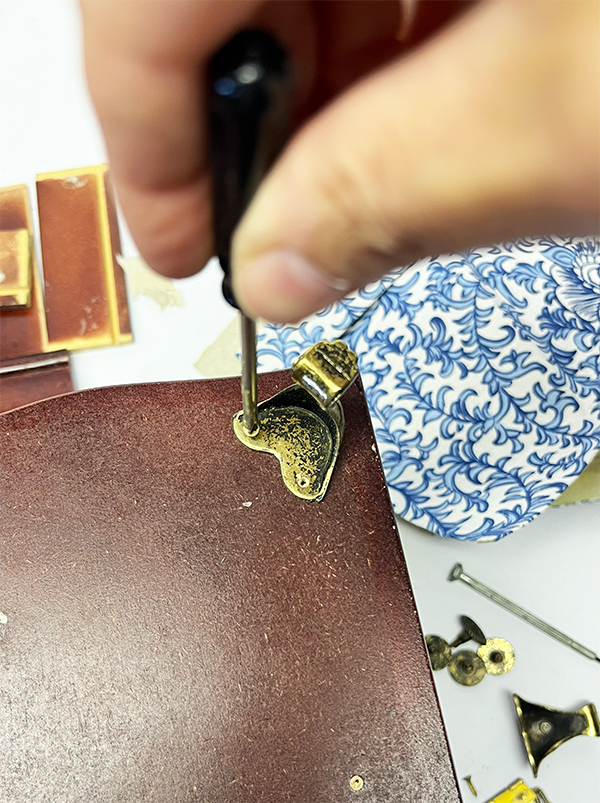 Removing the brass hardware from a thrift store jewelry box before sanding and painting.