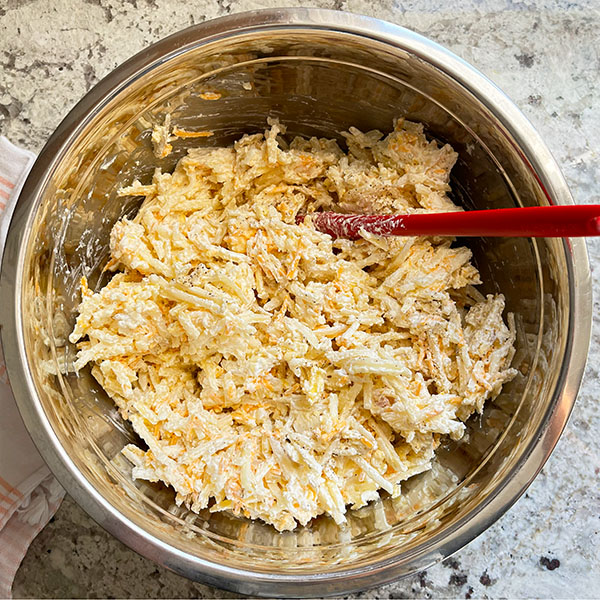 Stirring together the 5 ingredients in a metal mixing bowl to make a 13" x 9" casserole dish of Fresh from the oven cooling on a wood serving board, Baked Cheesy Hash Brown Potatoes.